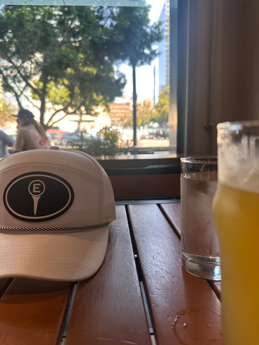 Estilo hat on a café table beside drinks and a window