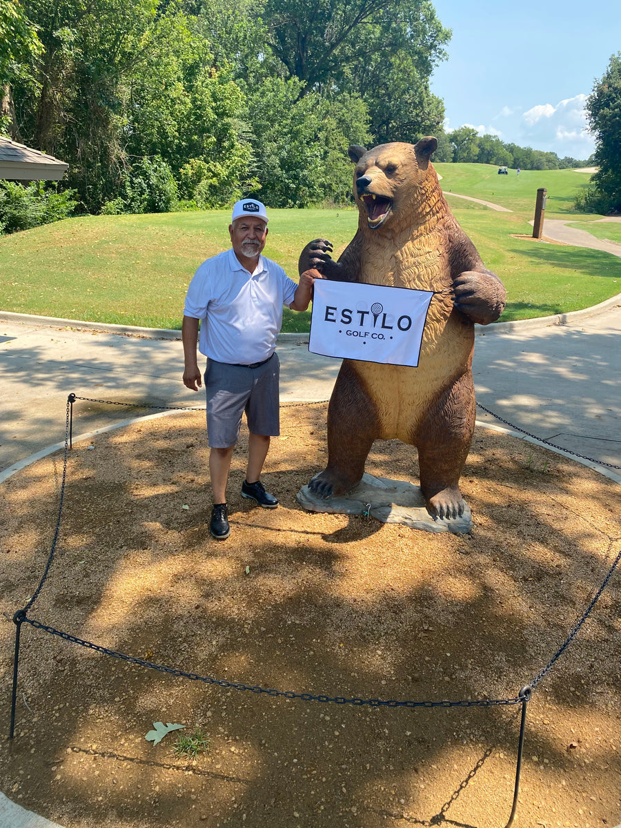 Estilo customer beside a bear statue holding an Estilo Golf Co. sign
